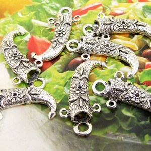 May include: Six silver-toned metal pendant charms shaped like a curved horn with a floral design. Each charm has three jump rings for attaching to jewelry.
