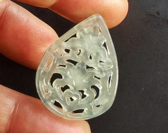 May include: A translucent green jade pendant carved with a delicate floral design. The pendant is shaped like a teardrop and has a smooth, polished finish.
