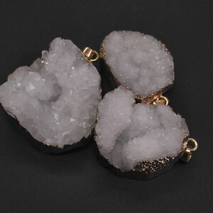 May include: Three white crystal quartz pendants with gold-toned metal accents. The pendants are shaped like clusters of crystals and have a rough, natural texture.