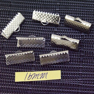 May include: Eight silver metal slider buckles, each measuring 16mm in length. The buckles have a textured surface and are designed to be used for straps or ribbon.