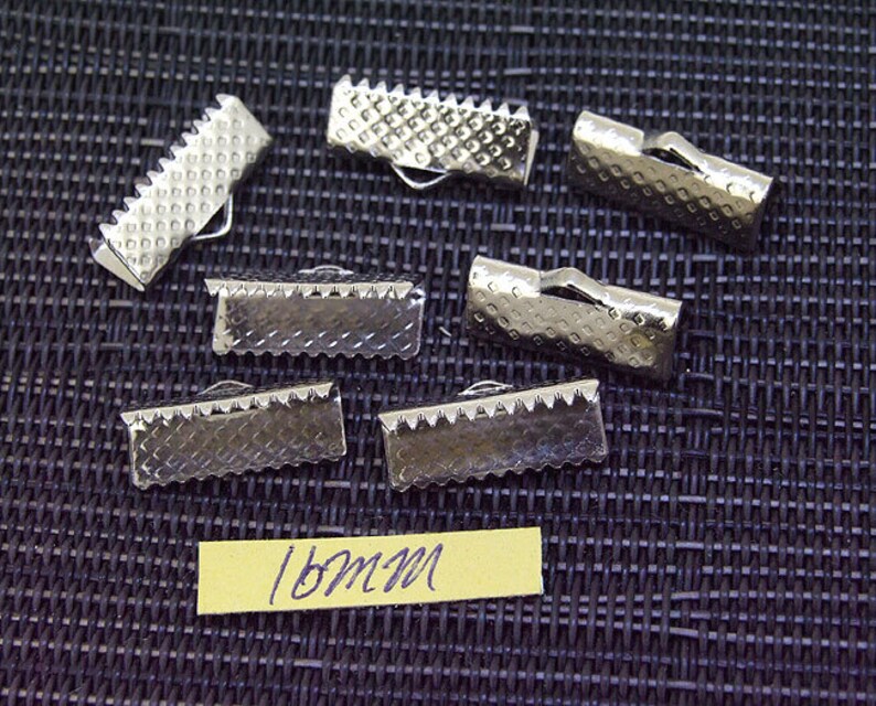 May include: Eight silver metal slider buckles, each measuring 16mm in length. The buckles have a textured surface and are designed to be used for straps or ribbon.