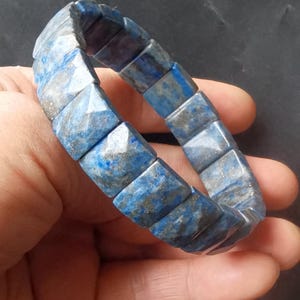 Op de afbeelding: Een blauwe en grijze lapis lazuli armband met gefacetteerde vierkante kralen.
