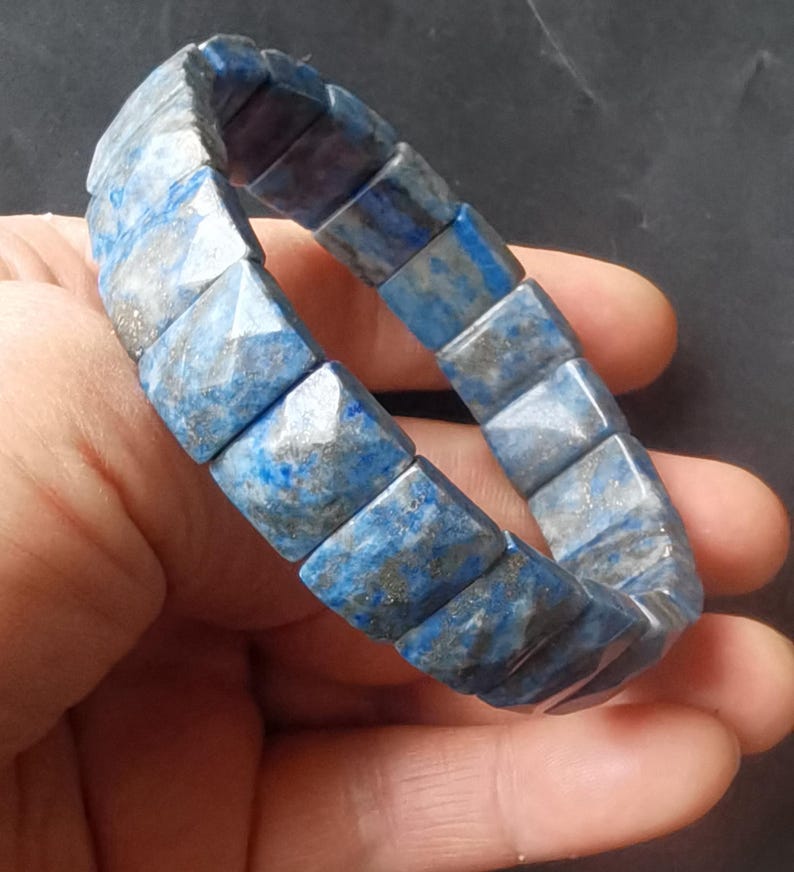 Op de afbeelding: Een blauwe en grijze lapis lazuli armband met gefacetteerde vierkante kralen.