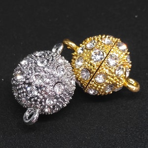 May include: Two round, silver and gold magnetic clasps with clear rhinestone accents. The clasps are designed to be used for jewelry making.
