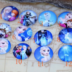Puede incluir: Doce cabujones redondos de vidrio con imágenes de personajes de la película animada Frozen. Las imágenes incluyen a Elsa, Anna, Olaf, Kristoff, Sven y otros personajes de la película.