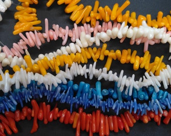 May include: A collection of coral beads in various colors, including orange, pink, white, blue, and red. The beads are arranged in rows, creating a colorful and textured display.