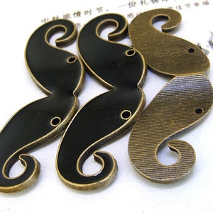 May include: Three black and gold metal mustache charms with a textured finish. The charms have two holes for attaching to a project.