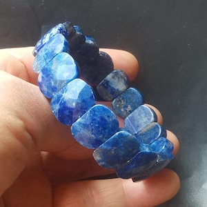 以下が含まれることがあります： ファセットカットされた長方形のビーズが付いた青いラピスラズリジェムストーンブレスレット