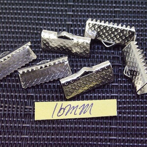 May include: Silver metal clasps with a textured surface and a serrated edge. The clasps are 18mm in size.