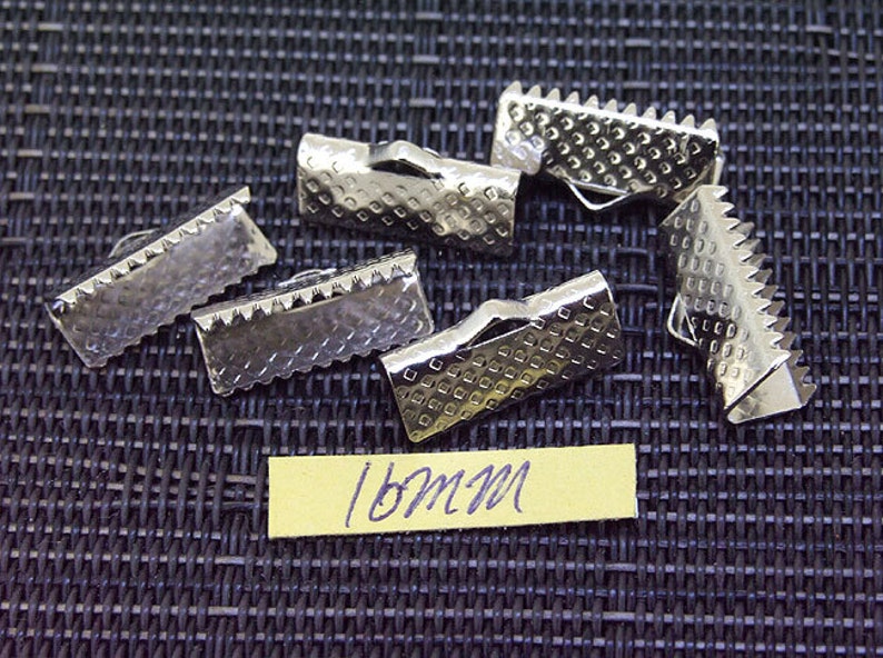 May include: Silver metal clasps with a textured surface and a serrated edge. The clasps are 18mm in size.