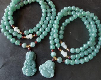 Puede incluir: Dos collares con cuentas esféricas de color verde claro y translúcido. Cada collar incluye pequeños detalles blancos en forma de calabaza, cuentas espaciadoras de color rojo oscuro y un colgante verde tallado con una figura sentada o un Buda sonriente.