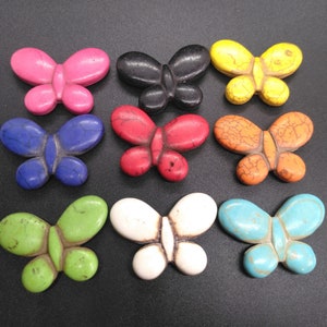 May include: Ten colorful butterfly-shaped beads made of natural stone. The beads are in various colors, including pink, black, yellow, red, orange, green, white, and blue.