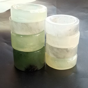 May include: A stack of five white jade rings, with a stack of four green jade rings next to them. The rings are smooth and polished, and they have a natural, organic look.