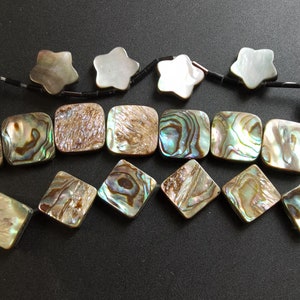 May include: A strand of iridescent abalone shell beads in a variety of shapes, including squares and stars. The beads are strung on a black cord.