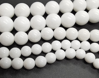 May include: A collection of white round beads of various sizes. The beads are smooth and polished, with a slight sheen.