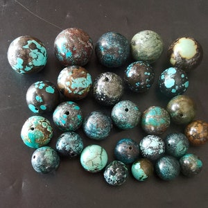 May include: A collection of 20 turquoise and black gemstone beads. The beads are round and have a speckled pattern.
