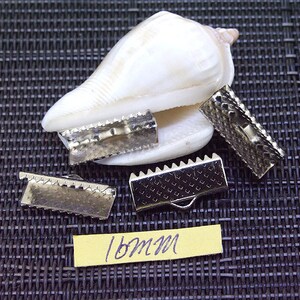 May include: Four silver metal slider buckles, each with a textured surface and a serrated edge. The buckles are 18mm in size and are arranged on a black textured surface.