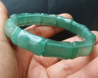 May include: A green jade bracelet made of smooth, rounded beads. The bracelet is made of natural stone and has a polished finish.