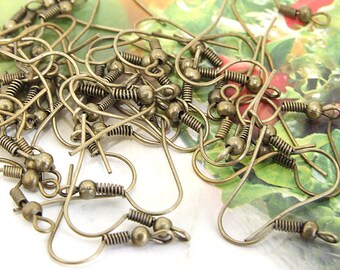 May include: A pile of antique brass earring hooks with a spring-loaded closure. The hooks are made of metal and have a round ball at the end.