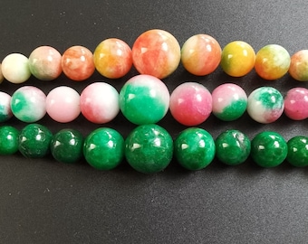 Puede incluir: Una hebra de cuentas de piedras preciosas de colores, con matices verdes, rosas y naranjas. Las cuentas son redondas y lisas, con un acabado pulido.