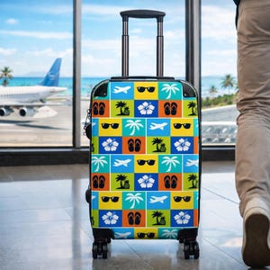 May include: A rolling suitcase featuring a grid pattern of colorful squares. Each square contains a white or black icon of an airplane, sunglasses, palm tree, hibiscus flower, pineapple, or flip-flops against blue, yellow, orange, or green backgrounds.