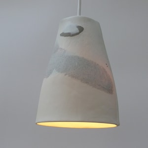 May include: A white ceramic pendant light with a textured surface and subtle gray and white abstract patterns.