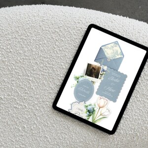 Op de afbeelding: Een digitale tablet met een trouwkaartenset bestaande uit een blauwe envelop, een polaroidfoto, bloemillustraties en de tekst Elodie & Marc. Het ontwerp bevat geschulpte randen, zachte blauwe tinten en afbeeldingen van tulpen.