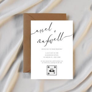 Puede incluir: Una invitaci&oacute;n de boda blanca con escritura negra, con los nombres "Ariel + Maxwell". La invitaci&oacute;n incluye detalles del evento y un c&oacute;digo QR, sobre un sobre marr&oacute;n y un fondo de tela color crema.