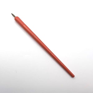 May include: A red craft knife with a pointed blade and a textured handle. The handle is a darker shade of red than the rest of the tool. The blade is a dark gray color.