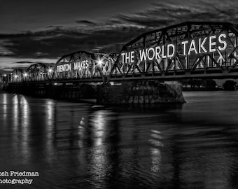 May include: A black and white photo of a bridge at night with the words "Trenton Makes The World Takes" illuminated on the bridge.