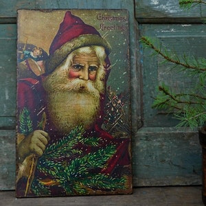 Peut inclure: Carte de No&euml;l vintage repr&eacute;sentant le P&egrave;re No&euml;l tenant une branche de sapin. La carte est dans les tons rouge, vert et or et comprend le texte "Christmas Greetings".