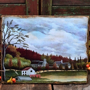 May include: A painting on wood depicting a small village with houses and trees under a cloudy sky. The painting is framed with a rustic wooden frame.