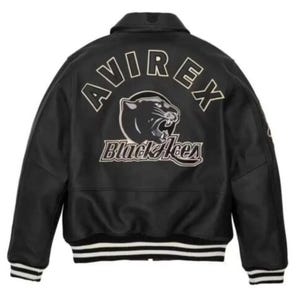 May include: A black varsity-style jacket featuring a collar, long sleeves, and ribbed cuffs and hem with white stripes. The back displays the text AVIREX in an arc above a graphic of a panther head and the text Black Aces in white lettering.