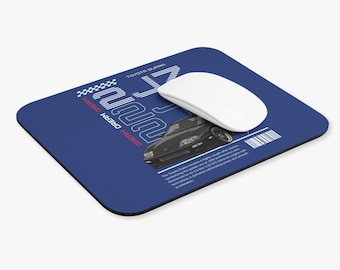 May include: A blue mousepad featuring a black Toyota Supra car graphic. The mousepad has the text "DREAM DREAM DREAM" and "17" in white and red. A white wireless mouse is on the mousepad.