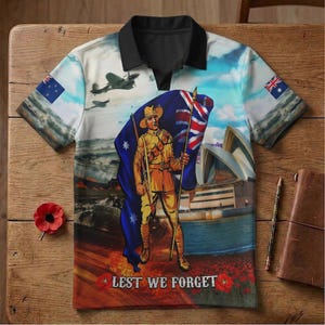 Könnte beinhalten: Ein Poloshirt mit einem patriotischen Design mit australischer Flagge, einem Soldaten und dem Sydney Opera House. Das Shirt hat ein blaues, weißes und beiges Farbschema mit dem Text "Lest We Forget" am unteren Rand.