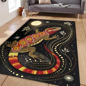 Puede incluir: Alfombra negra con un diseño estilizado de lagarto en tonos rojos, amarillos y dorados. El lagarto está adornado con patrones intrincados. La alfombra tiene un tema de cielo nocturno con una luna y líneas punteadas.