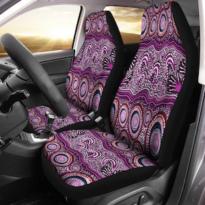Puede incluir: Fundas de asiento de coche con un vibrante patrón morado y blanco. El diseño presenta formas circulares y onduladas en tonos morado, rosa y blanco, sobre un fondo negro. Las fundas están diseñadas para los asientos delanteros de un coche.