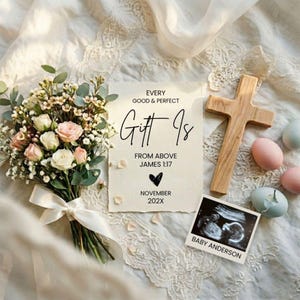 May include: A bouquet of white and pink roses with greenery, a wooden cross, and a sonogram photo. A card reads "Every good & perfect gift is from above James 1:17" with a heart and the month and year.