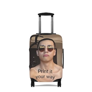 Op de afbeelding: Een rolkoffer met een persoon met een zonnebril. De koffer heeft een beige achtergrond met de tekst "Print it your way" in het zwart. Hij heeft een zwarte handgreep en wielen.