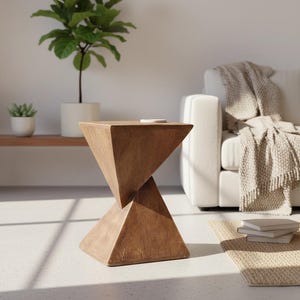Puede incluir: Una mesa auxiliar de madera marrón con un diseño geométrico de reloj de arena. La mesa está hecha de madera maciza y tiene un acabado natural. Se encuentra en un salón con un sofá blanco, una planta y una alfombra.