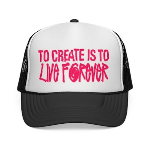 May include: A trucker hat with a white front panel and black mesh back. The front features the text TO CREATE IS TO LIVE FOREVER printed in a bold, bright pink, hand-drawn style font. The hat has a solid black brim and a black button on top.