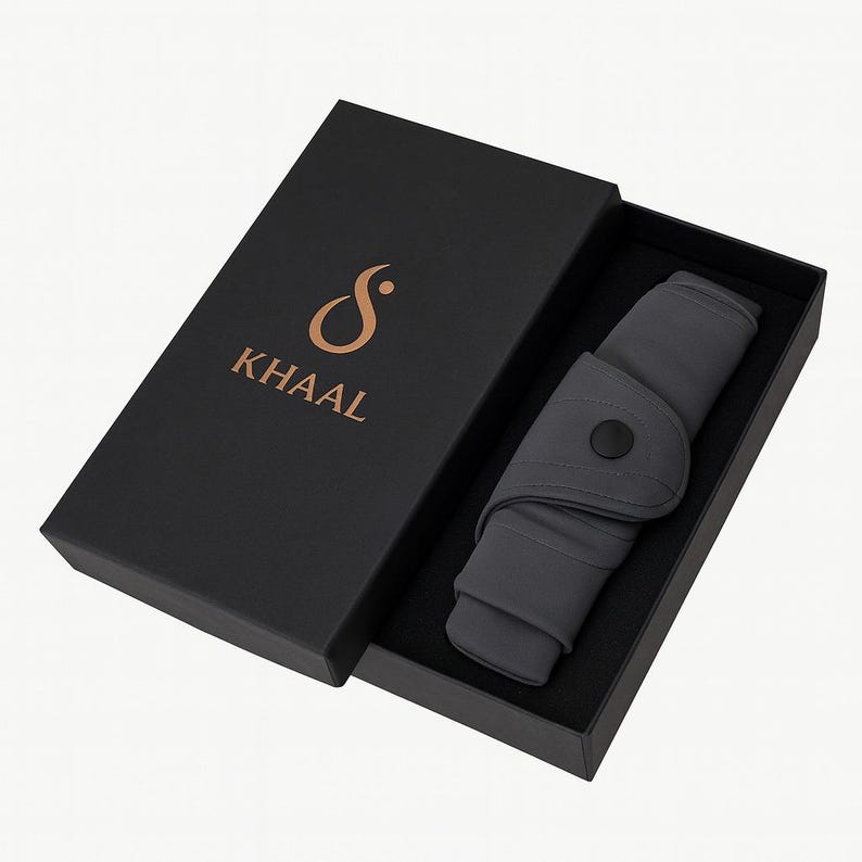 May include: A dark gray product is displayed inside a black box. The product is folded and secured with a black button. The box has the word "KHAAL" in gold lettering.