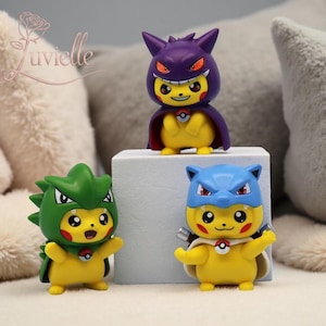 May include: Three yellow figurines of a popular character, each wearing a different colored costume. The costumes are green, blue, and purple. Each figurine has a red cheek and a red and white emblem on its chest.
