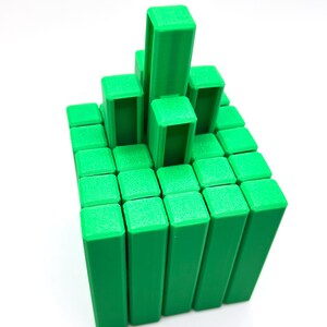 May include: A green 3D-printed puzzle game with a grid of rectangular blocks. Some blocks are stacked higher than others, creating a tiered structure. The blocks are a solid, vibrant green color, and the background is white.