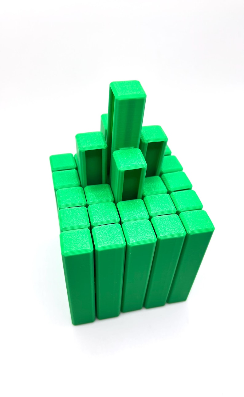 May include: A green 3D-printed puzzle game with a grid of rectangular blocks. Some blocks are stacked higher than others, creating a tiered structure. The blocks are a solid, vibrant green color, and the background is white.