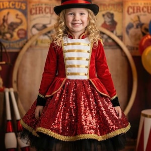 Può includere: Un costume a tema circo per bambini. La giacca in velluto rosso ha finiture dorate e pannelli bianchi con strisce dorate. La gonna è ricoperta di paillettes rosse, con una sottogonna in tulle nero. Un cappello a cilindro nero con una fascia rossa completa il look.