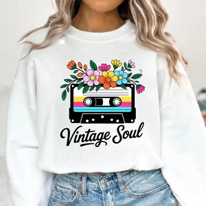 May include: White sweatshirt with a retro cassette tape design, adorned with flowers and the words "Vintage Soul". The cassette tape design features bright colours and a floral arrangement.