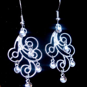 Peut inclure: Boucles d'oreilles pendantes en argent avec un motif en spirale et plusieurs perles rondes. Les boucles d'oreilles sont en argent et ont un design d&eacute;licat et complexe.