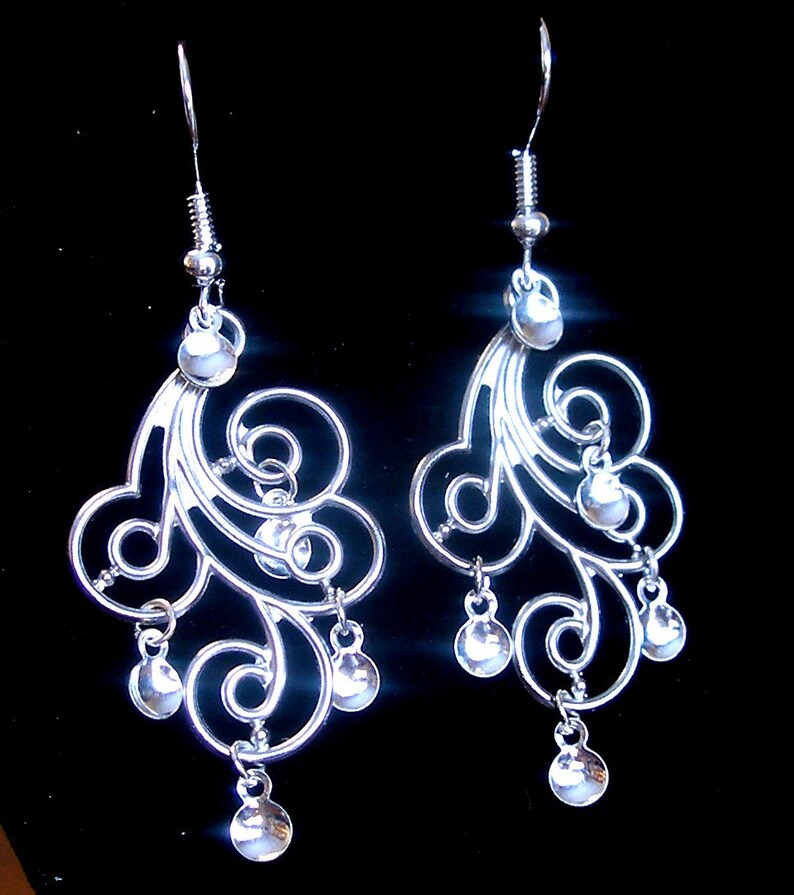 Peut inclure: Boucles d'oreilles pendantes en argent avec un motif en spirale et plusieurs perles rondes. Les boucles d'oreilles sont en argent et ont un design d&eacute;licat et complexe.