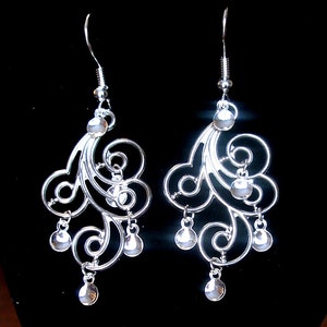 Peut inclure: Boucles d'oreilles pendantes en argent avec un design d&eacute;licat et tourbillonnant et plusieurs petites perles rondes.
